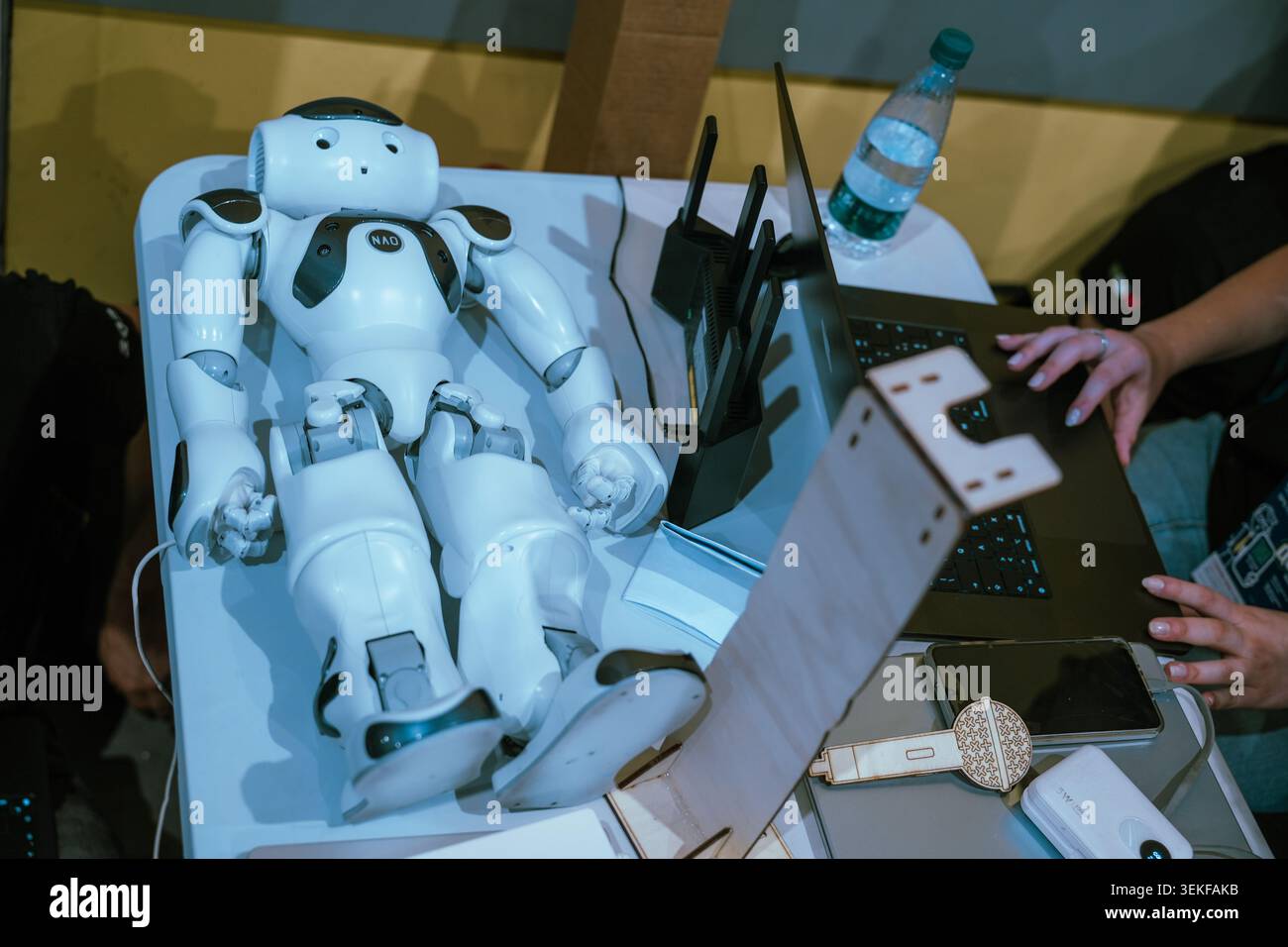 Ein Team von Schülern programmiert und testet einen kleinen humanoiden NAO-Roboter während eines pädagogischen Roboterwettbewerbs. Stockfoto