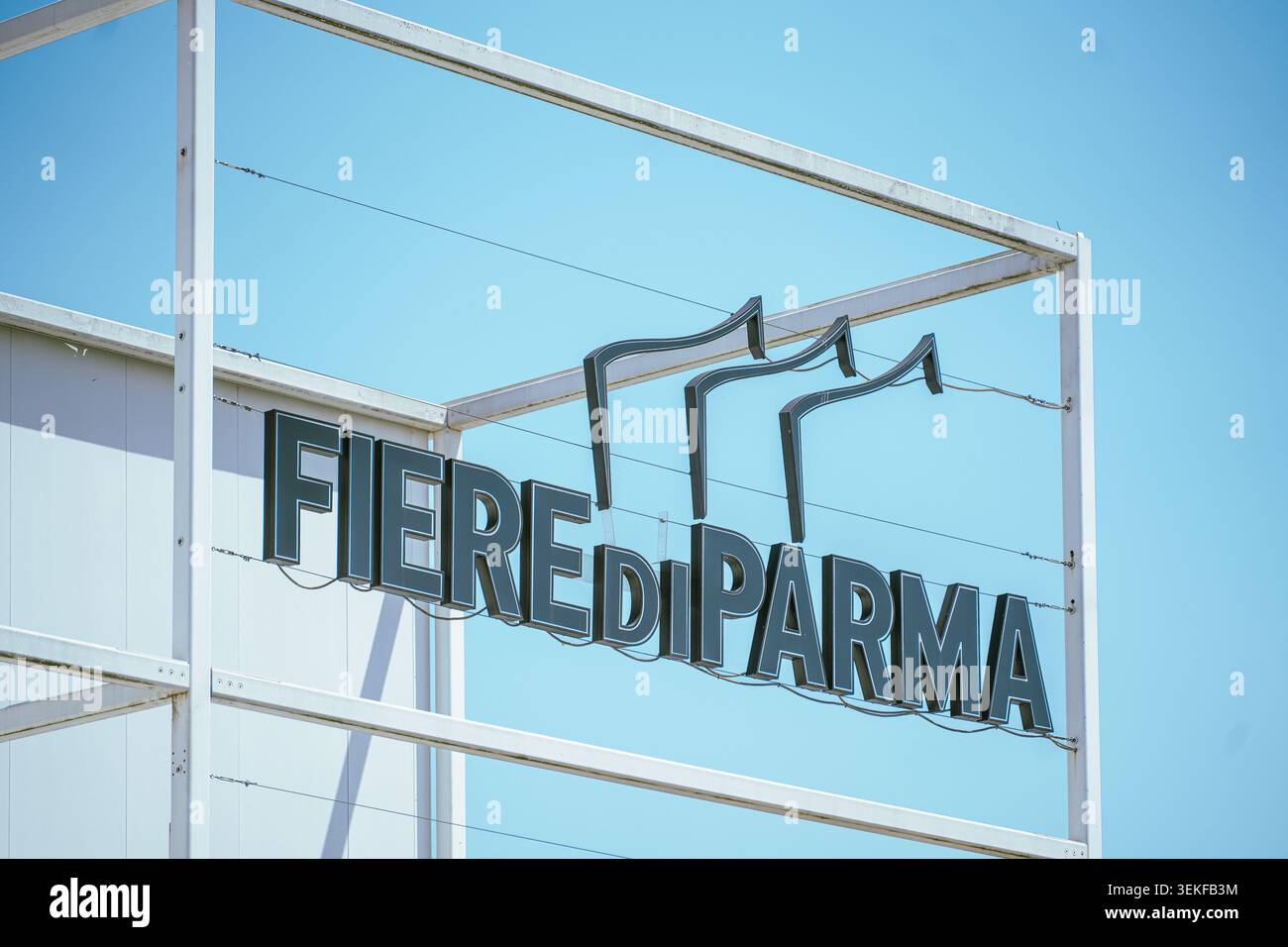 Die markante institutionelle Außenbeschilderung für das Messezentrum „Fiere di Parma“ ist auf einem weißen Strukturrahmen vor einem klaren blauen Himmel montiert Stockfoto