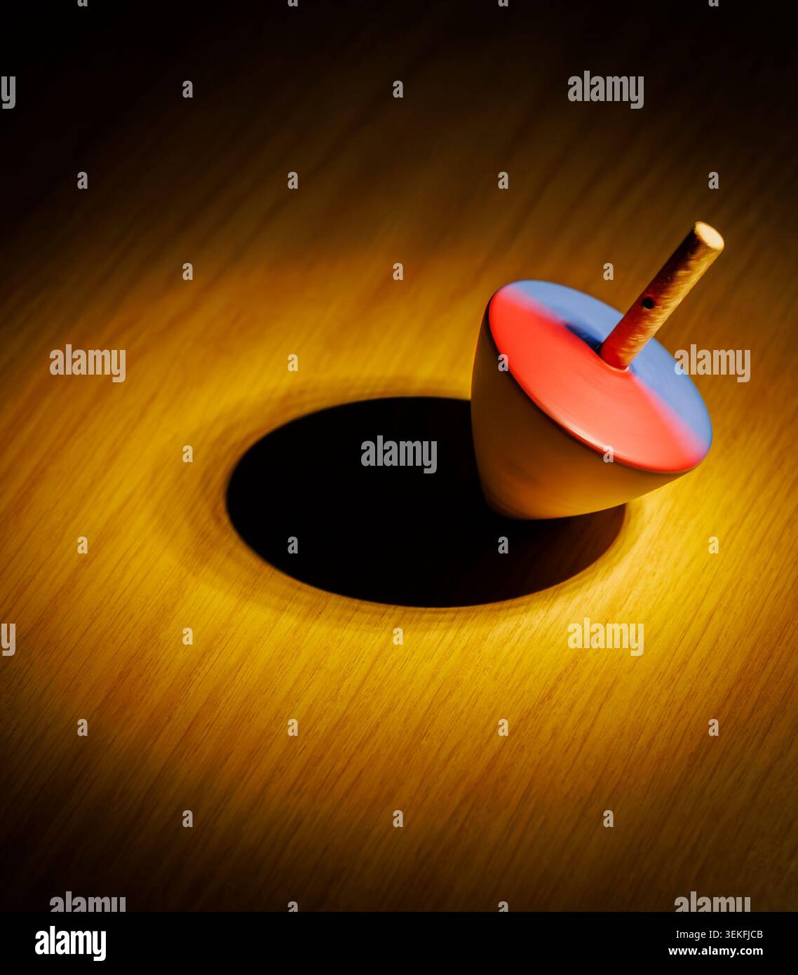 Eine hölzerne Decke, die sich in einem Pool aus Licht dreht und kinetische Energie demonstriert Stockfoto
