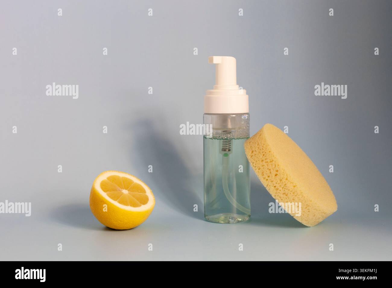 Schaumreiniger Flasche mit Zitrone und Schwamm auf blauem Hintergrund Stockfoto
