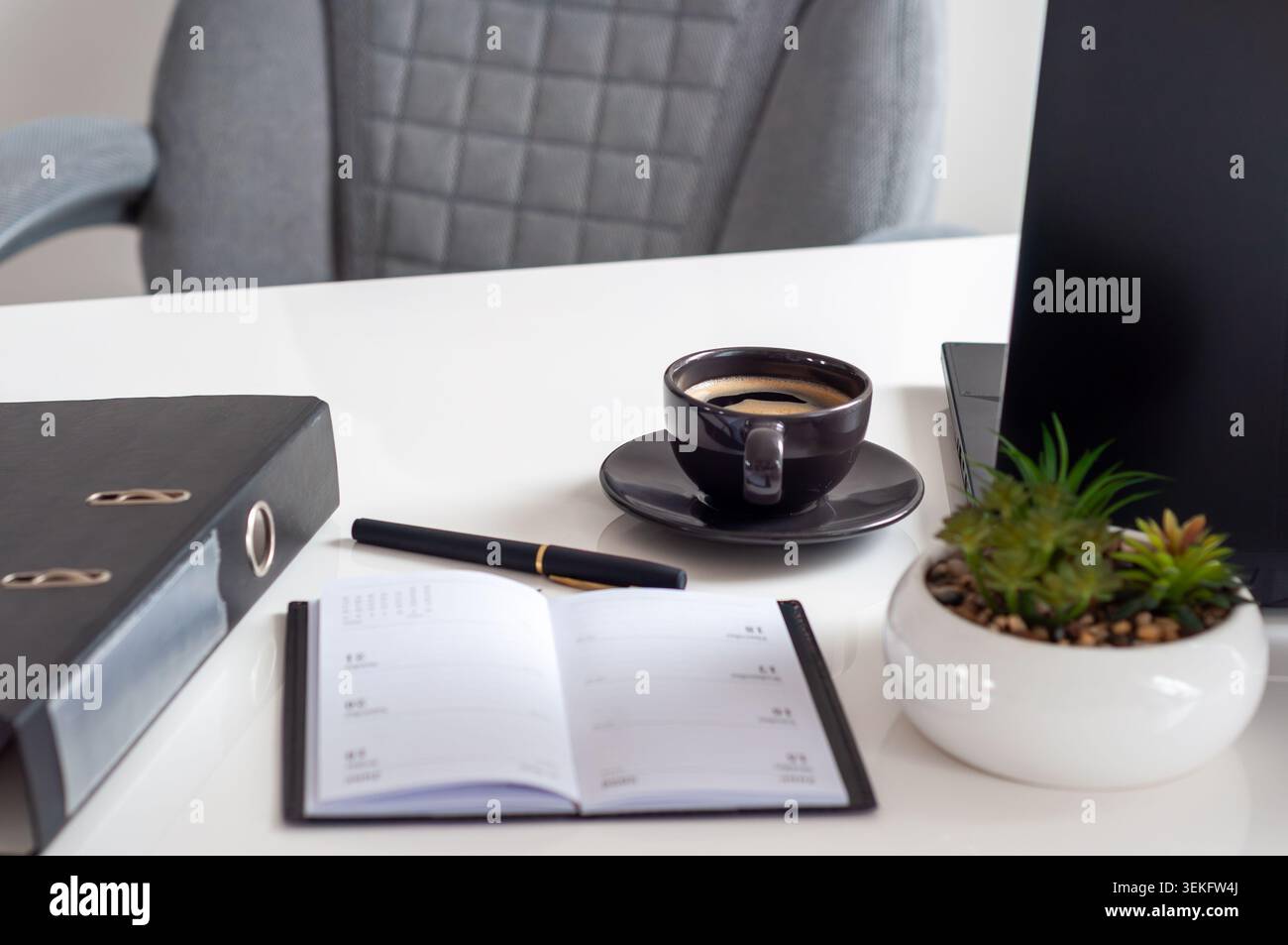 Der offene Planer liegt neben Kaffee und Stift Stockfoto