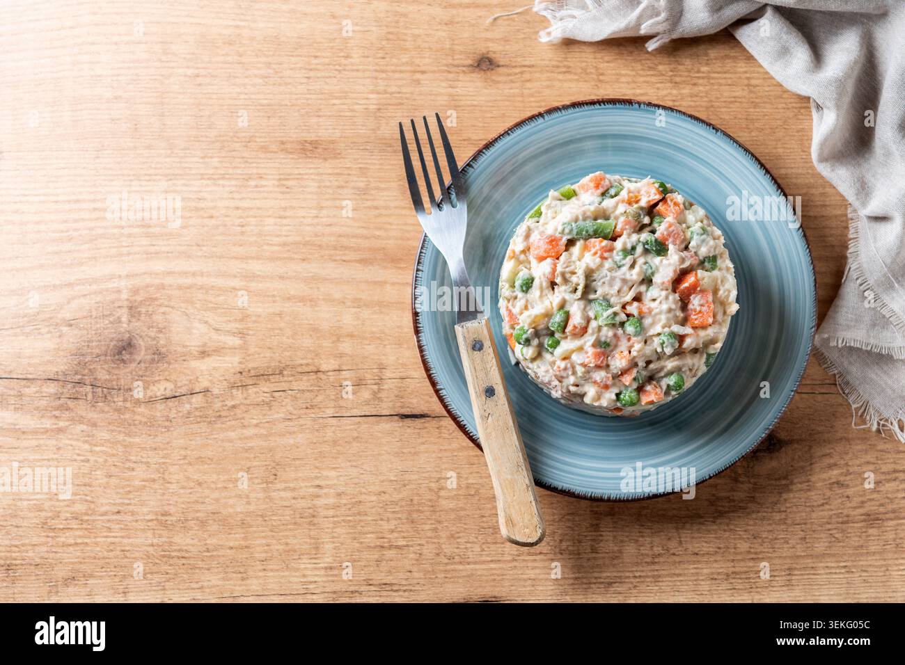 Traditioneller russischer Salat auf einem blauen Teller über einem Holztisch. Stockfoto