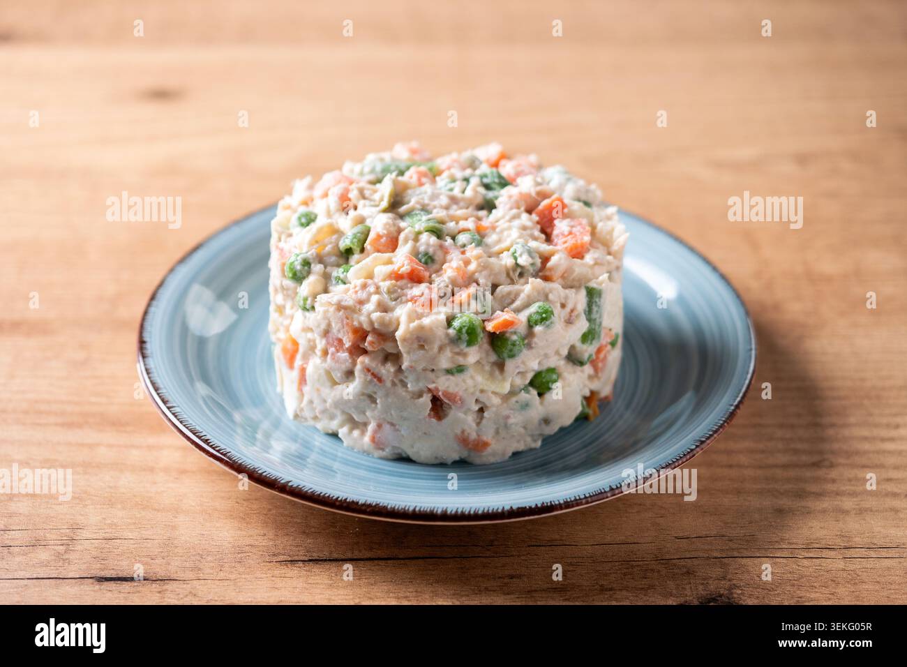 Traditioneller russischer Salat auf einem blauen Teller über einem Holztisch. Stockfoto