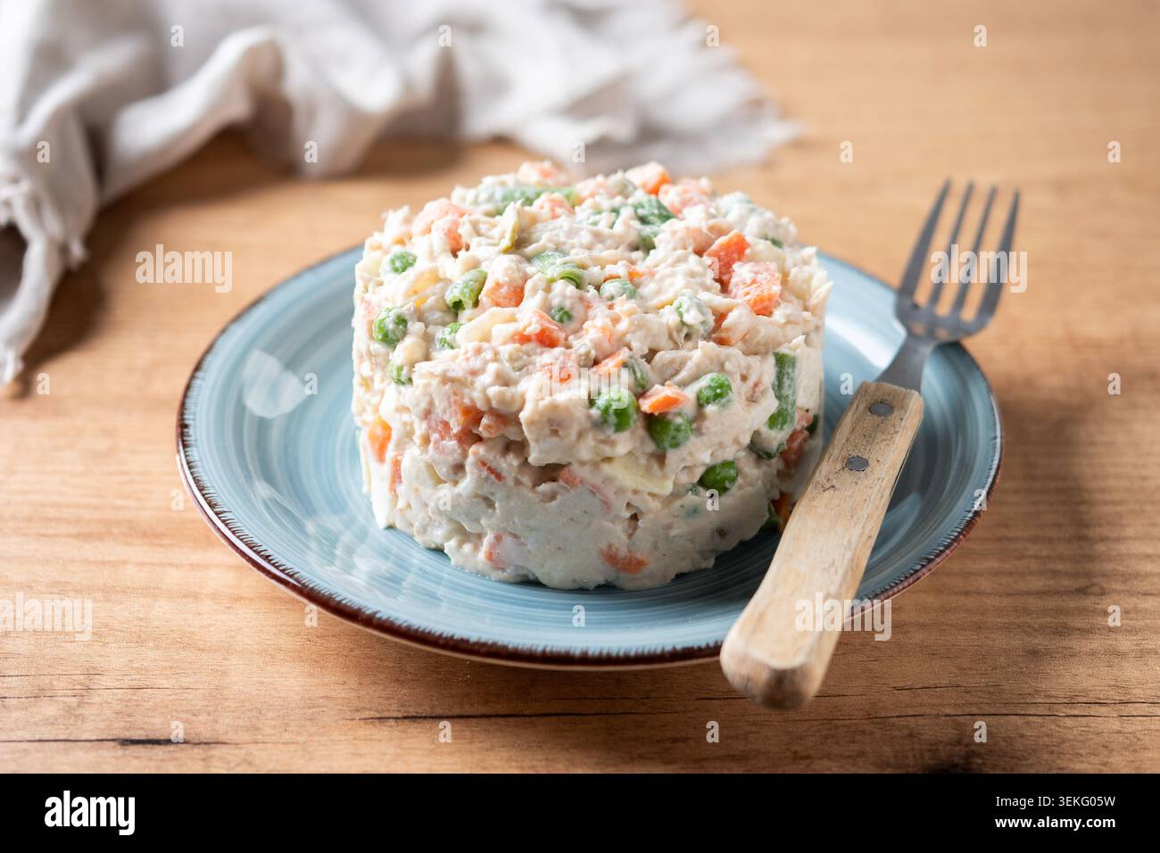 Traditioneller russischer Salat auf einem blauen Teller über einem Holztisch. Stockfoto