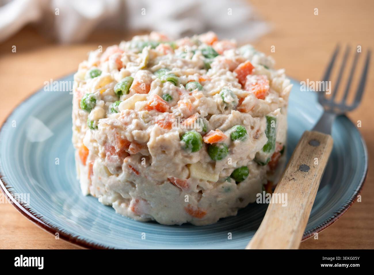 Traditioneller russischer Salat auf einem blauen Teller über einem Holztisch. Stockfoto