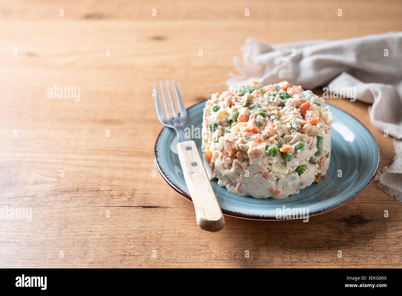 Traditioneller russischer Salat auf einem blauen Teller über einem Holztisch. Stockfoto