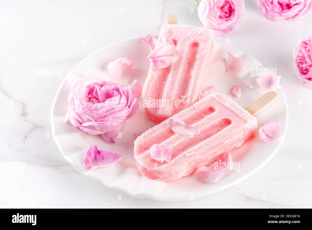 Süße Kräuterrose Eis Lollies in Sticks, leckerer cremiger Tee Rose Blumen gefrorenes Dessert mit Rosenknospen auf weißem Marmor Tisch Backgr Stockfoto
