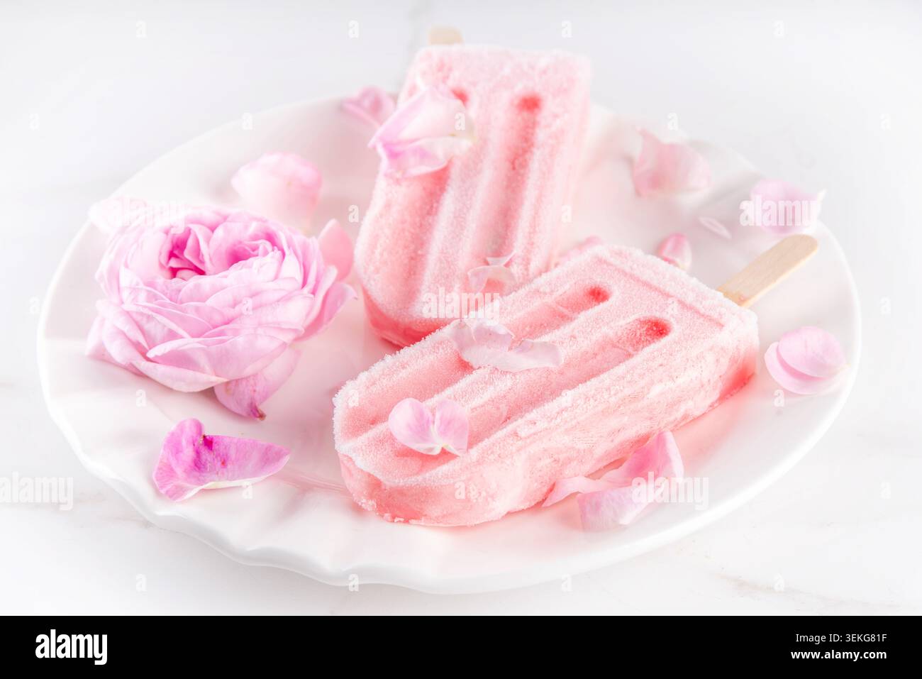 Süße Kräuterrose Eis Lollies in Sticks, leckerer cremiger Tee Rose Blumen gefrorenes Dessert mit Rosenknospen auf weißem Marmor Tisch Backgr Stockfoto