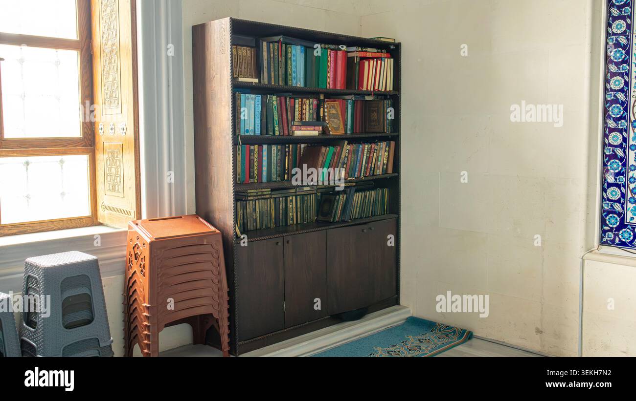 ISTANBUL, Türkiye - 30. April 2026. Basaksehir Millet Camii. Ein dunkles hölzernes Bücherregal zeigt verschiedene Ausgaben des Heiligen Korans und der islamischen Literatur Stockfoto