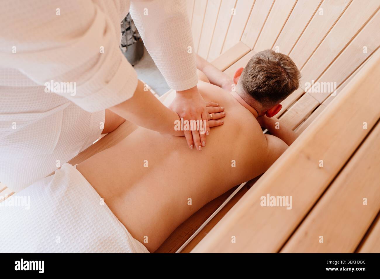 Weiße Frau, Die Den Mann Während Der Sauna-Massage Zurückdrückt Stockfoto
