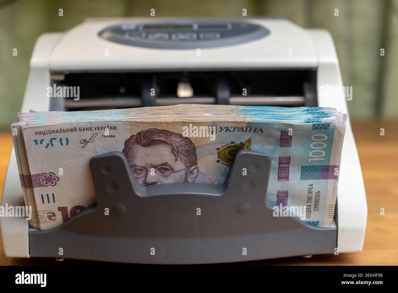 Nahaufnahme eines automatischen Bargeldzählautomaten, beladen mit einem Stapel von 1000 ukrainischen Griwna-Banknoten. Finanz- und Bankkonzept, Währungsumtausch Stockfoto