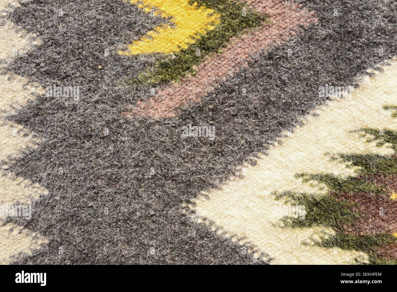 Wollgewebe mit traditionellem ethnischem Ornament und weicher Filzoberfläche. Rustikaler Textilhintergrund mit geometrischem Muster und Naturfasern. Stockfoto