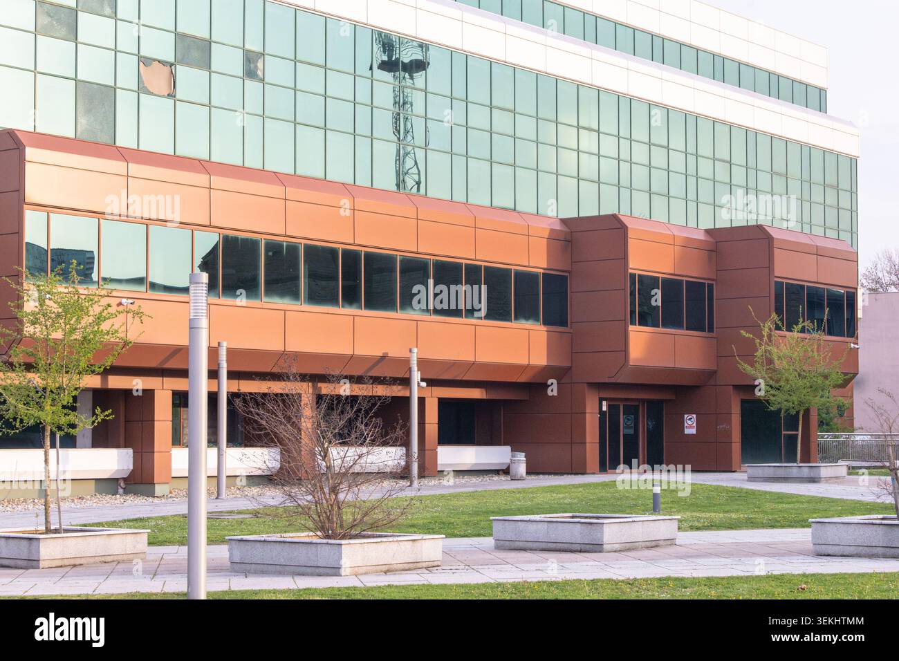 Vinkovci, Kroatien - 03.April 2026: Modernes Bürogebäude aus Glas mit reflektierender grüner Fassade, mit Blick auf eine ruhige städtische Kreuzung in der Abenddämmerung Stockfoto