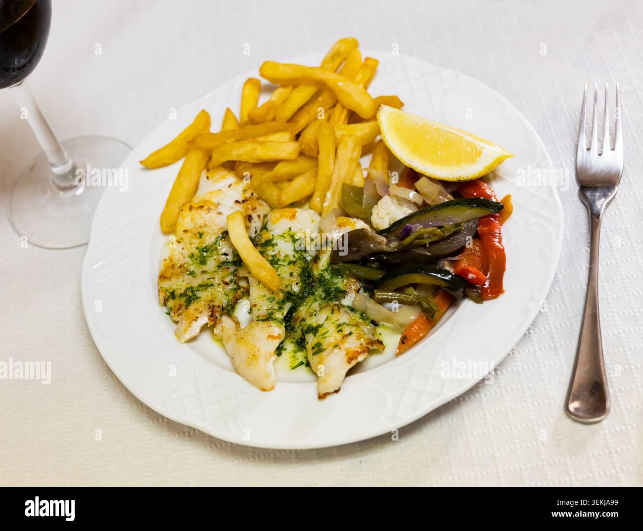 Der Teller enthält gebratenes rosafarbenes Aalfilet, ergänzt durch Pommes Frites und gebackenes Gemüse Stockfoto