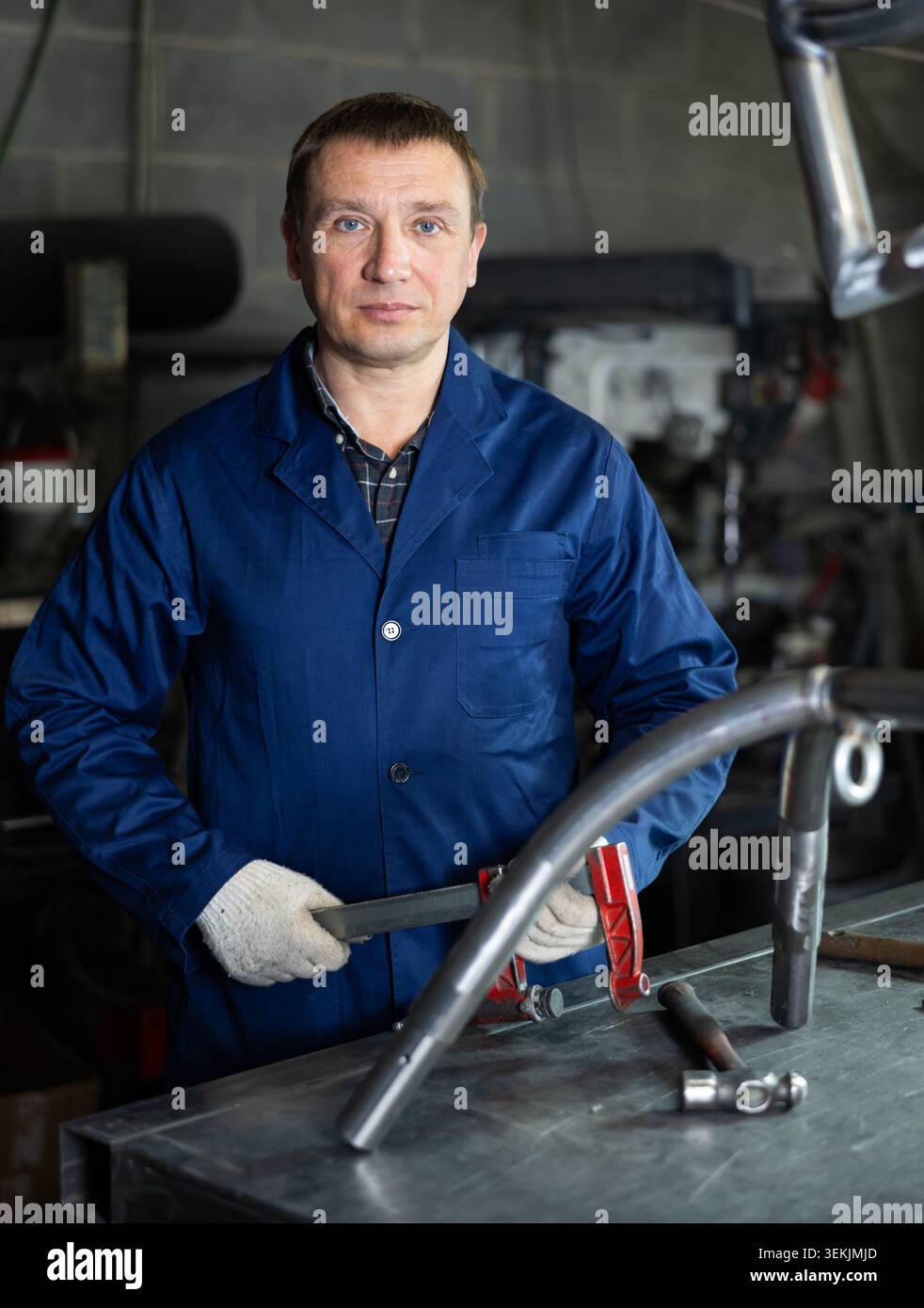 Arbeiter der Metallwerkstatt, der am Arbeitsplatz mit Klammer steht Stockfoto