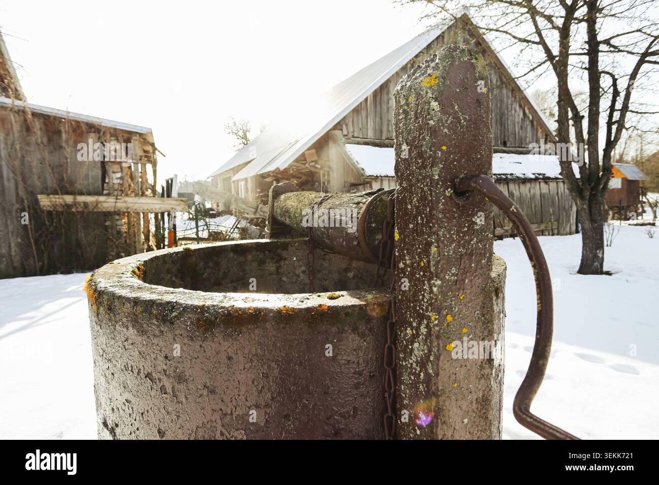 Altes ländliches Wasser im Winter gut mit Schnee bedeckt. Traditioneller ländlicher Hintergrund mit historischer Dorfarchitektur und saisonaler Landschaft. Stockfoto