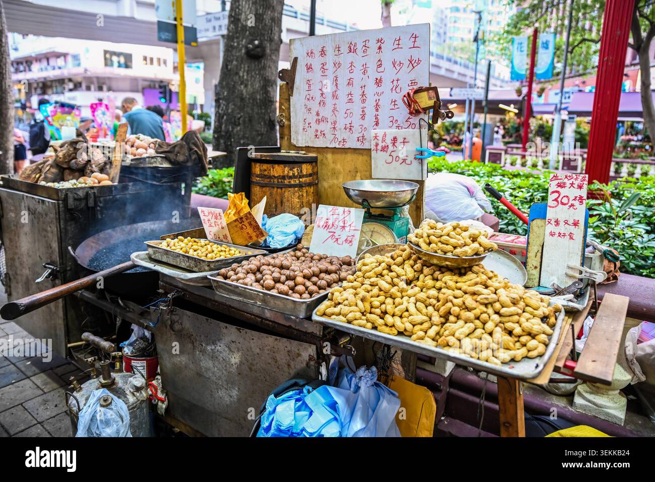 HONGKONG, CHINA, 21. April 2026, ein traditioneller Street Food Cart auf einem Bürgersteig zeigt geröstete Erdnüsse Macadamia und Ginkgo Nüsse mit handgeschriebenen Preisen Stockfoto