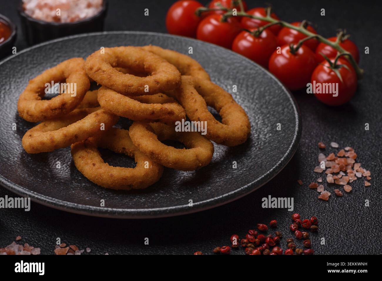 Zwiebelringe oder gebratener Tintenfisch in Brotkrumen mit Sauce, Essen zum Mitnehmen. Gebratene Zwiebelringe, Fast Food als Hintergrund für Ihr Design Stockfoto