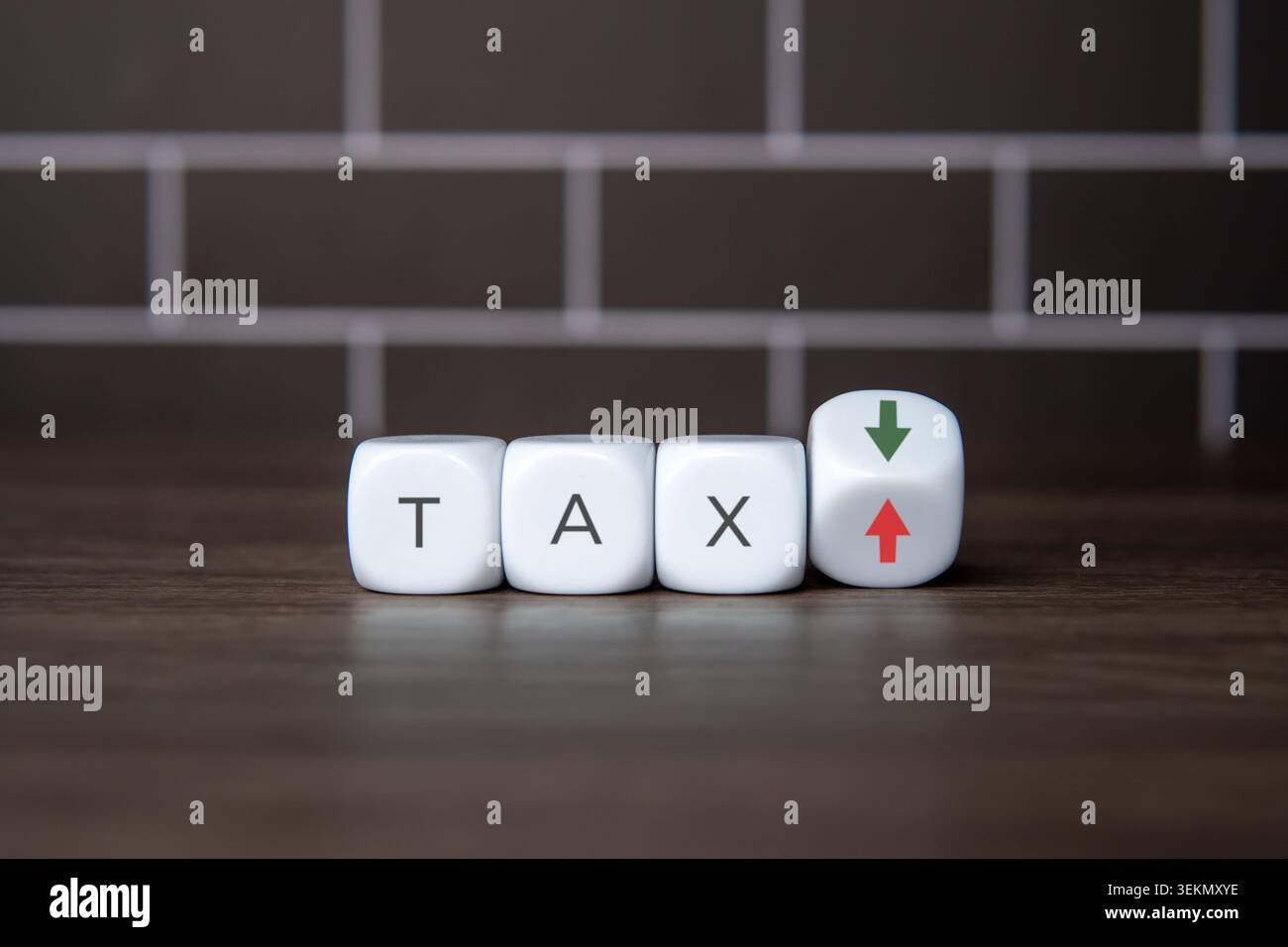 Weiße Blöcke, die das Wort „TAX“ neben einem geneigten Würfel mit grünen nach unten und roten nach oben zeigenden Pfeilen beschreiben. Steuersenkungen, Steuererhöhungen, Finanzplanung, Stockfoto