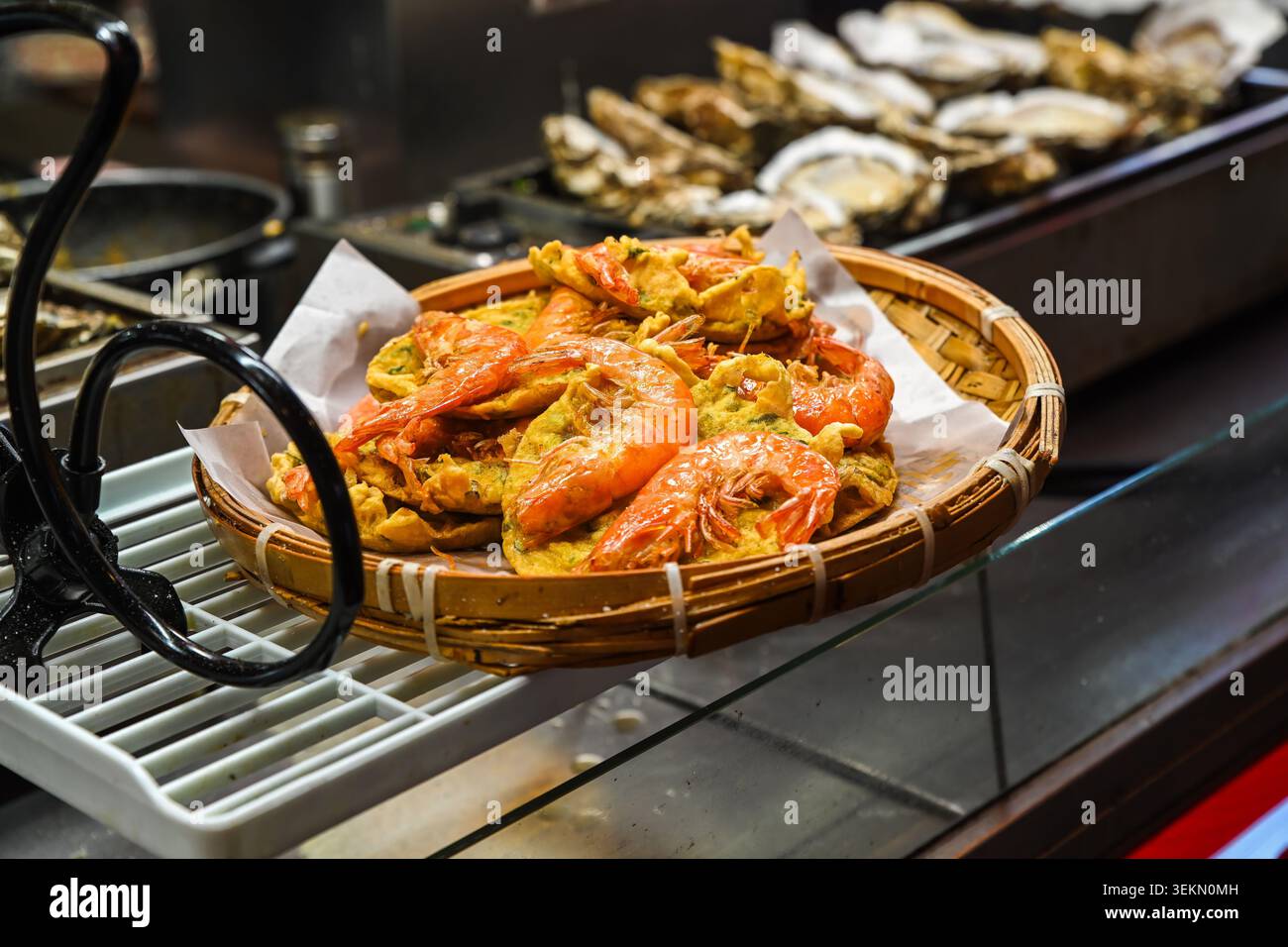 Knusprige gebratene Garnelenkuchen auf Bambuskorb zum Verkauf am Temple Street Night Market Street Food Stand unter Abendlichtern in Hong Kong Tierwelt Stockfoto