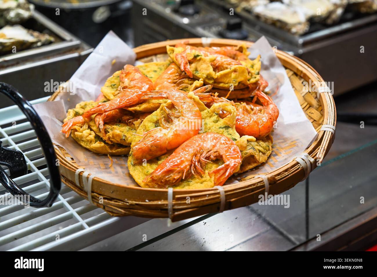 Knusprige gebratene Garnelenkuchen auf Bambuskorb zum Verkauf am Temple Street Night Market Street Food Stand unter der Abendsonne in Hongkong Stockfoto