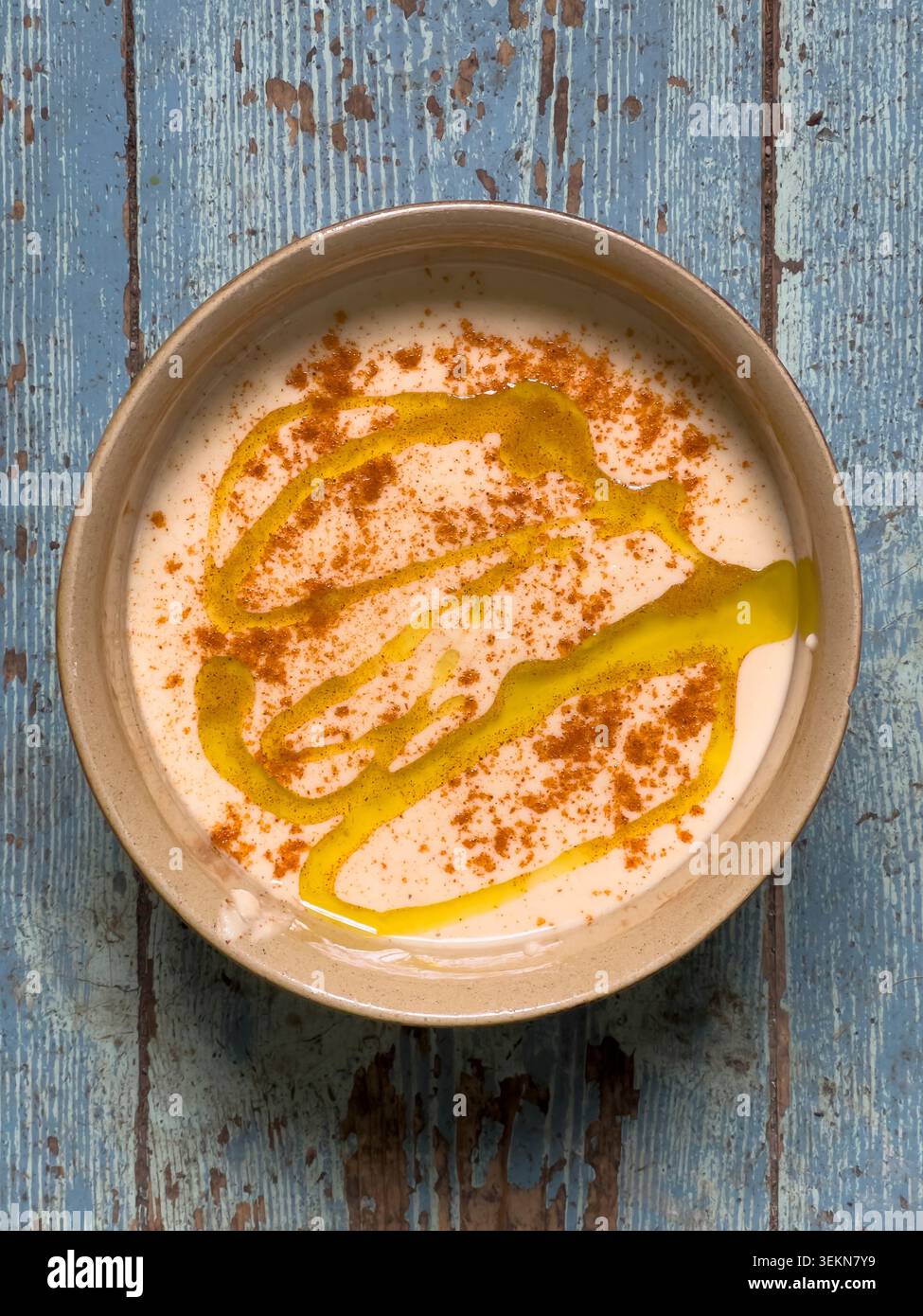 Nahaufnahme einer Schüssel mit frisch zubereitetem Hummus (hummous), mit Olivenöl getränkt und mit Paprika bestreut Stockfoto