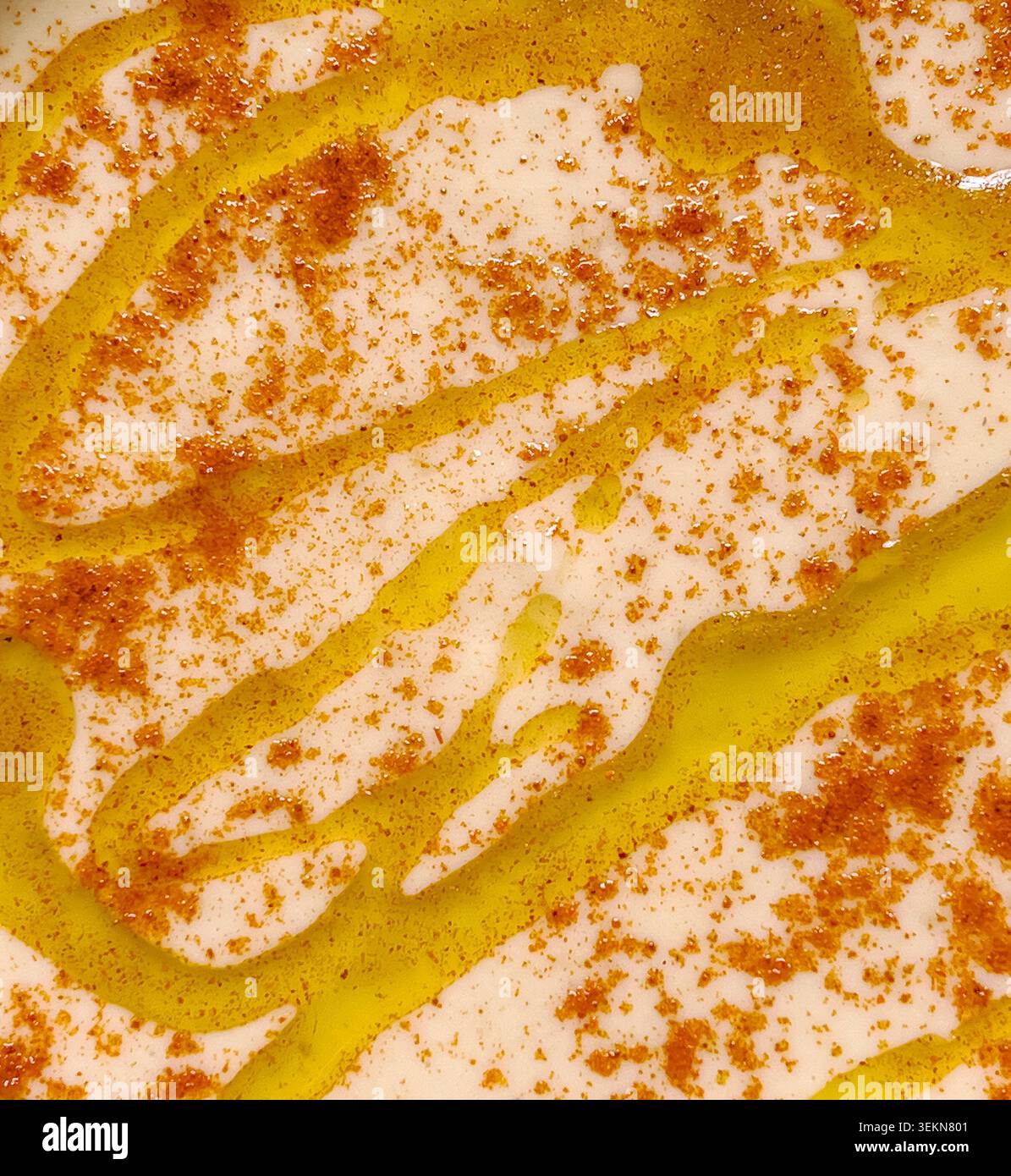 Nahaufnahme einer Schüssel mit frisch zubereitetem Hummus (hummous), mit Olivenöl getränkt und mit Paprika bestreut Stockfoto