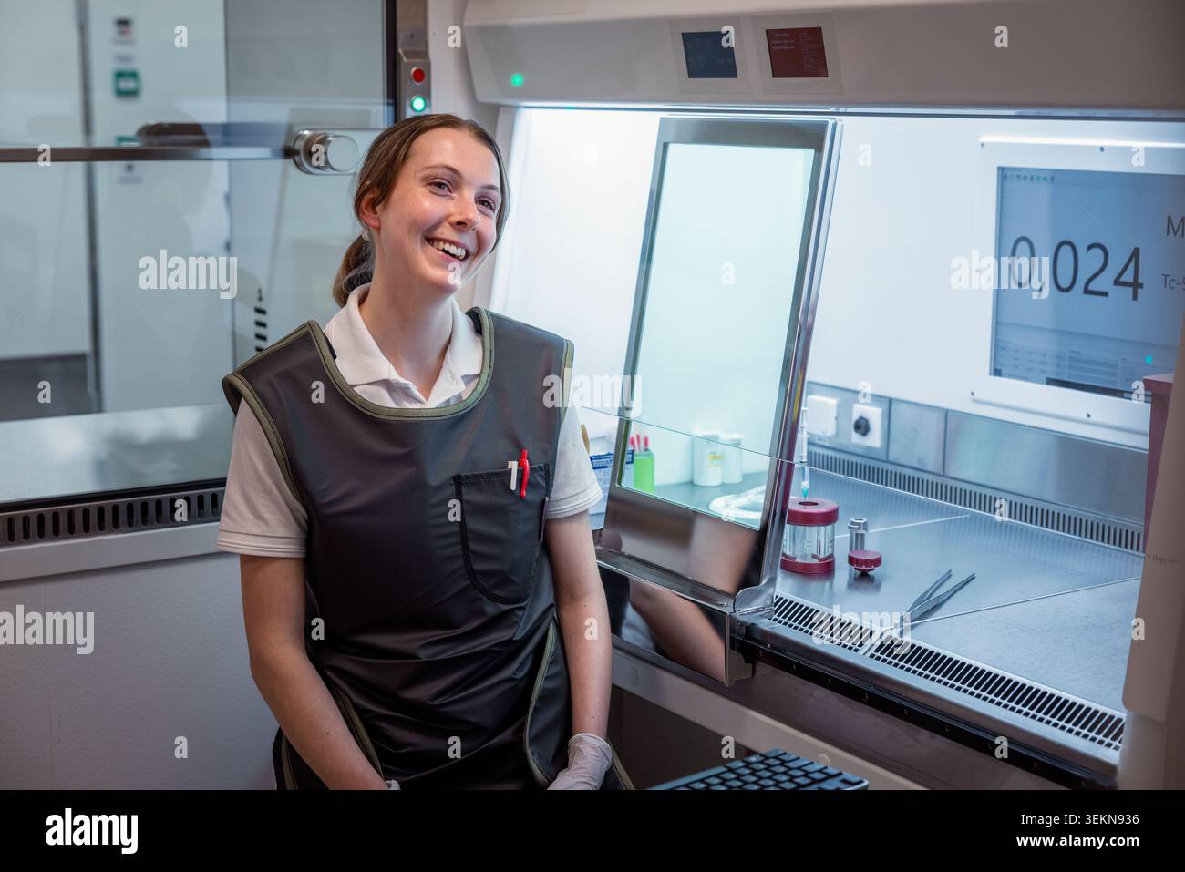 Lächelnder junger Wissenschaftler, der in der Nähe eines Laminarkabinetts im Labor sitzt Stockfoto