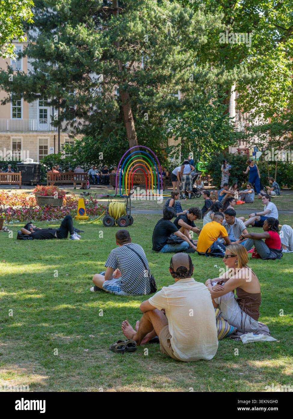 London, Vereinigtes Königreich - 11. Juli 2025: Gruppen von Menschen entspannen auf dem Gras und finden Schatten von Bäumen auf einem beliebten londoner Platz während der Hitzewelle oder Stockfoto