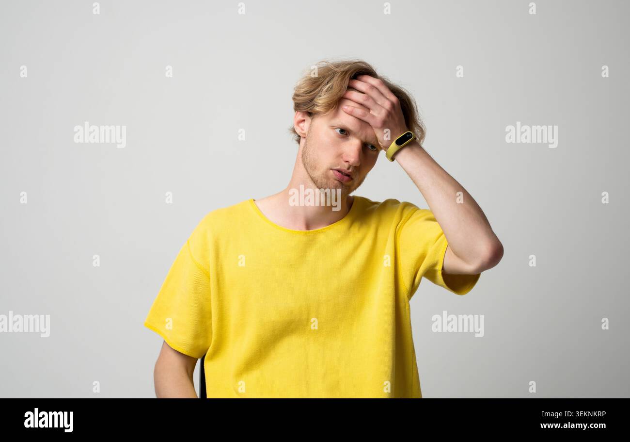 Junger Mann, der unter starken Kopfschmerzen oder Migräne leidet, intensive Schmerzen und Unwohlsein in der Stirn spürt, Stress, Krankheit, Erschöpfung erlebt Stockfoto