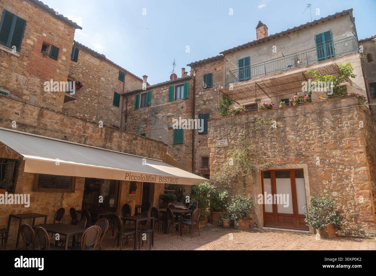 Gemütliches Hofcafé in einer historischen italienischen Stadt mit Steinmauern und Sitzgelegenheiten im Freien. Warme mediterrane Atmosphäre perfekt für Reisen, Freizeit und Stockfoto