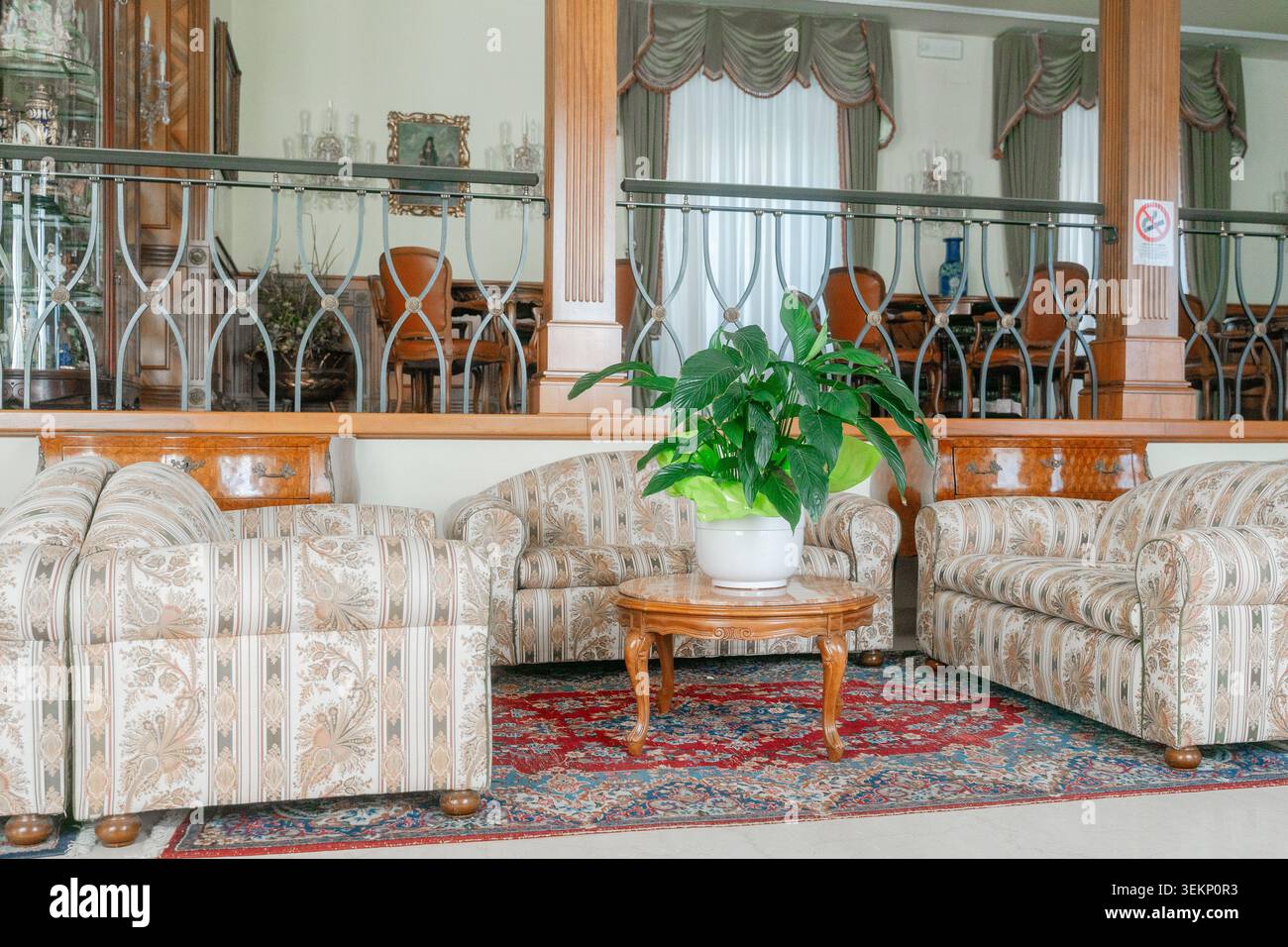 Klassische Lounge-Einrichtung mit Sofa, Pflanzen- und dekorativen Elementen. Warme Atmosphäre mit Komfort und traditionellem europäischem Design. Stockfoto