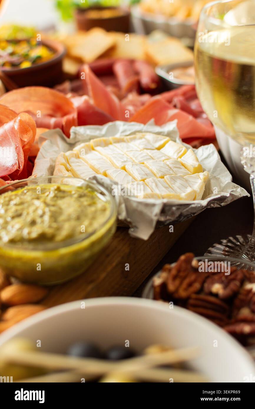 Versammelt um eine wunderschön gestaltete Wurstplatte gefüllt mit verschiedenen Käsesorten, köstlichen Würstchen, cremigem Hummus und frischen Trauben. Perfekt für Stockfoto