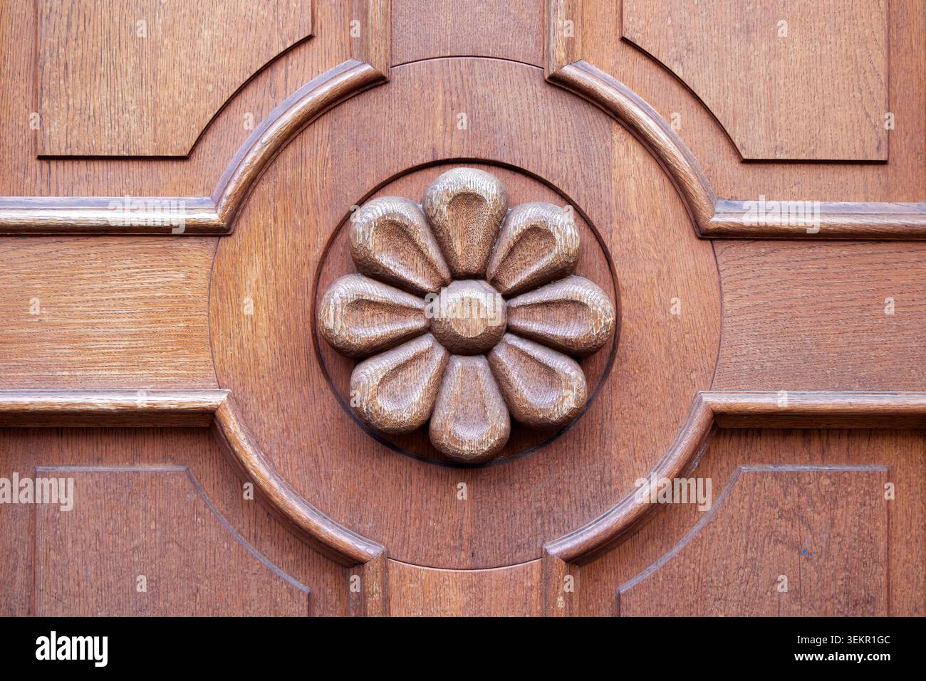 Eine Nahaufnahme einer geschnitzten Holzblume auf einer braunen Vintage-Tür oder Möbelplatte. Stockfoto