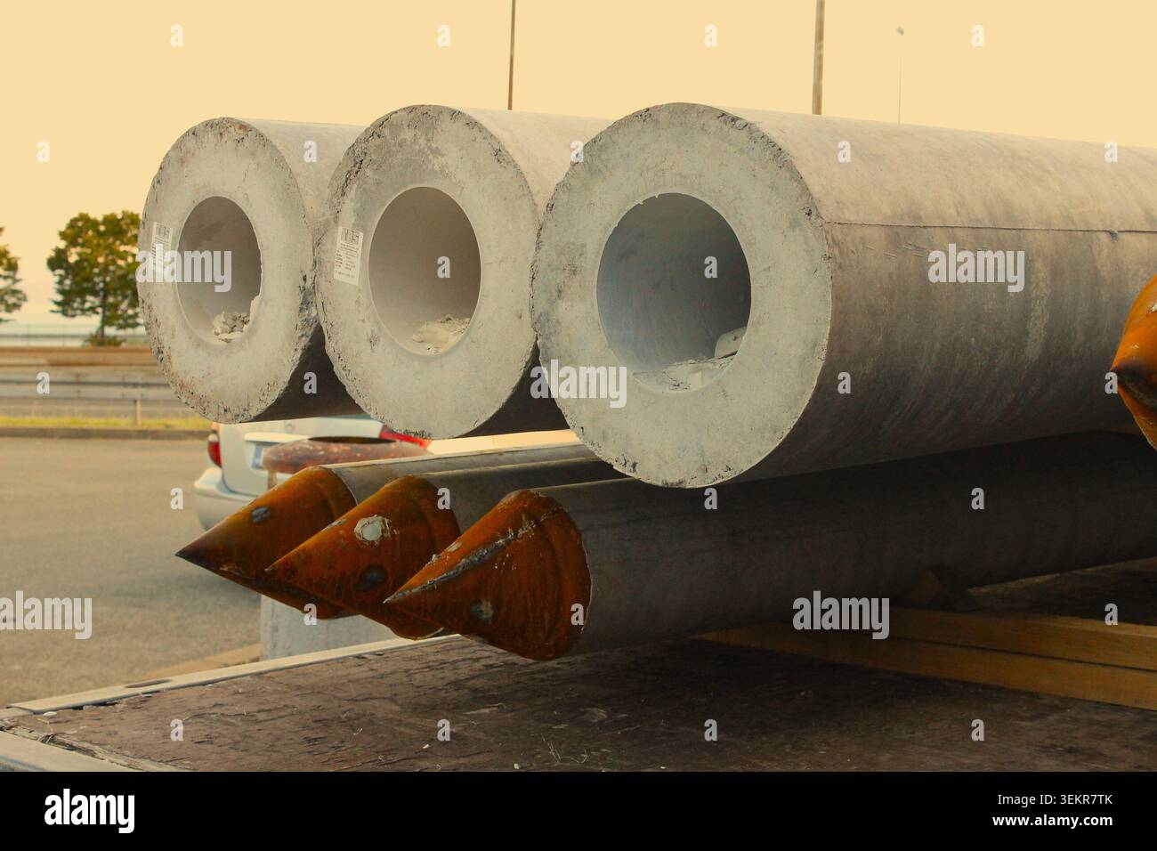 Große Betonhohlstapel, die auf einem Tieflader gestapelt sind, mit rostigen spitzen Metallspitzen, die in der unteren Reihe auf einer Baustelle sichtbar sind. Stockfoto