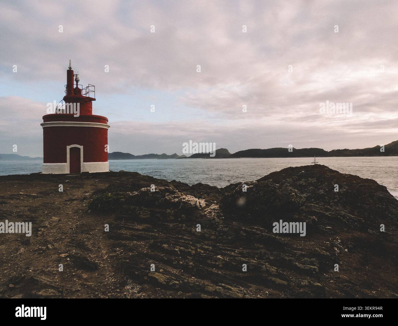 Der berühmte leuchtend rote Punta Robaleira Leuchtturm auf den zerklüfteten Felswänden von Costa da Vela, Cangas, Galicien, Spanien. Atlantik Stockfoto