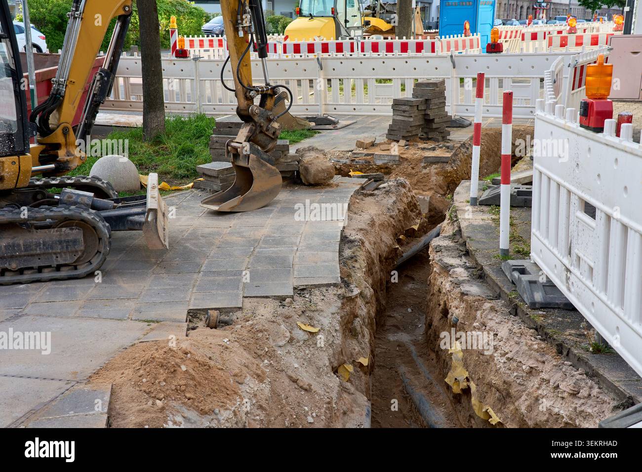 Minibagger auf der Baustelle Urban Roadworks mit Tiefengraben für Rohre Stockfoto