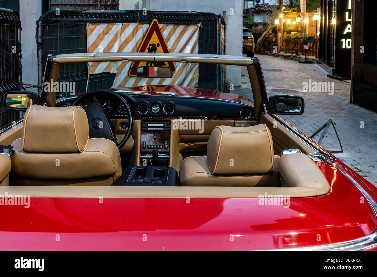 Das Armaturenbrett im Innenraum und die braunen Ledersitze eines Mercedes-Benz SL Cabriolets in Vintage-Rot sind auf einer Straße in Tirana, Albanien, zu sehen. Stockfoto