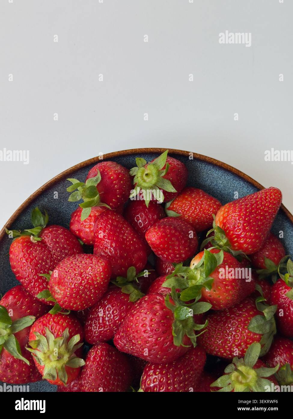 Frische Erdbeeren in der Keramikschale Weißer Hintergrund Overhead View Copy Space. Frischer Backround - Smartphone-aufgenommenes Stockfoto