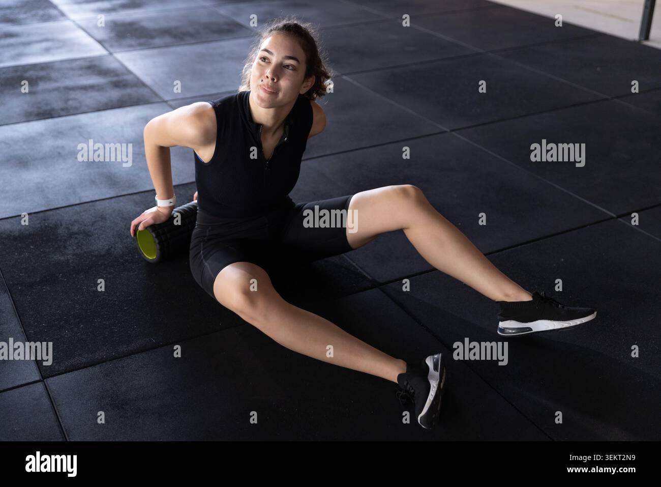 Weiblich Mitte Zwanziger mit Schaumstoffrolle und schwarzem Sporttop und Shorts im Fitnessstudio Stockfoto