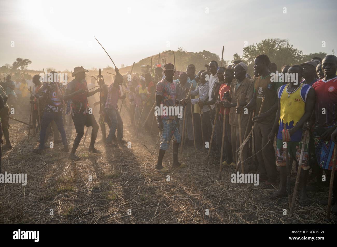 Nuba-Leute mit Stöcken versammeln sich auf einem staubigen Feld, beobachten und nehmen an einem traditionellen Ringen teil. Stockfoto