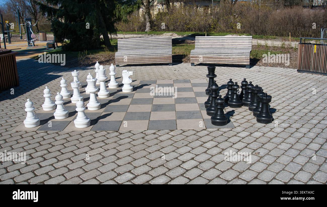 Riesiges Freiluftschach in einem öffentlichen Stadtpark mit Holzbänken Stockfoto