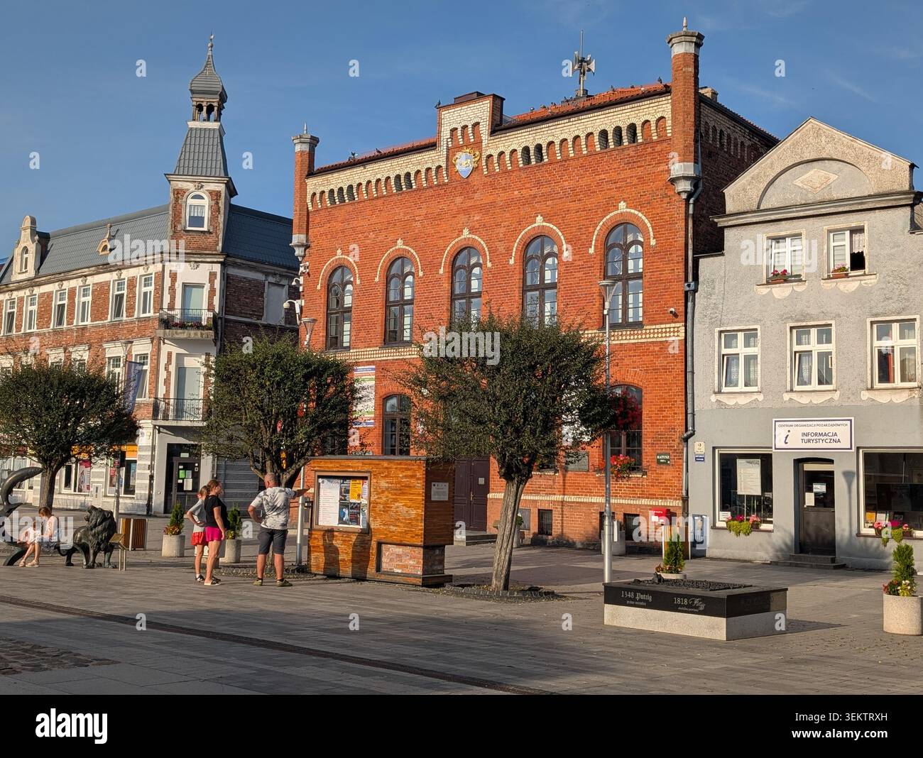 PUCK, POLEN - 14. August 2025: Blick auf das historische neogotische Rathaus aus dem 19. Jahrhundert (Ratusz) am Alten Marktplatz. Die rote Backsteinarchitektur zeigt das Stadtwappen und lokale Flaggen an einem sonnigen Sommertag. - Smartphone-aufgenommenes Stockfoto