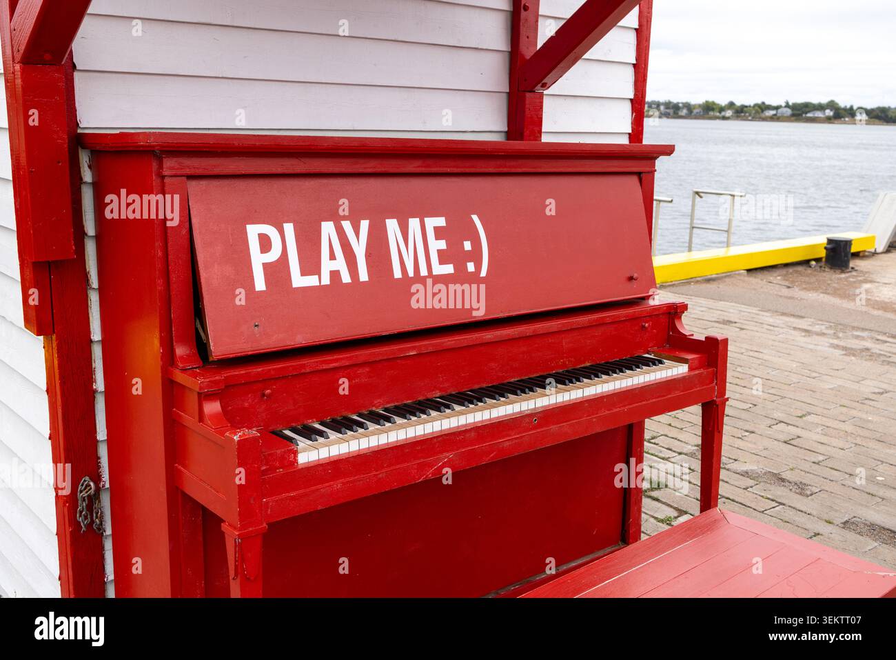 Rotes öffentliches Klavier neben einer Uferpromenade in Nova Scotia Kanada, das Besucher zum Musikspielen und Genießen eines kreativen Gemeinschaftsraumes in der Nähe des Har einlädt Stockfoto