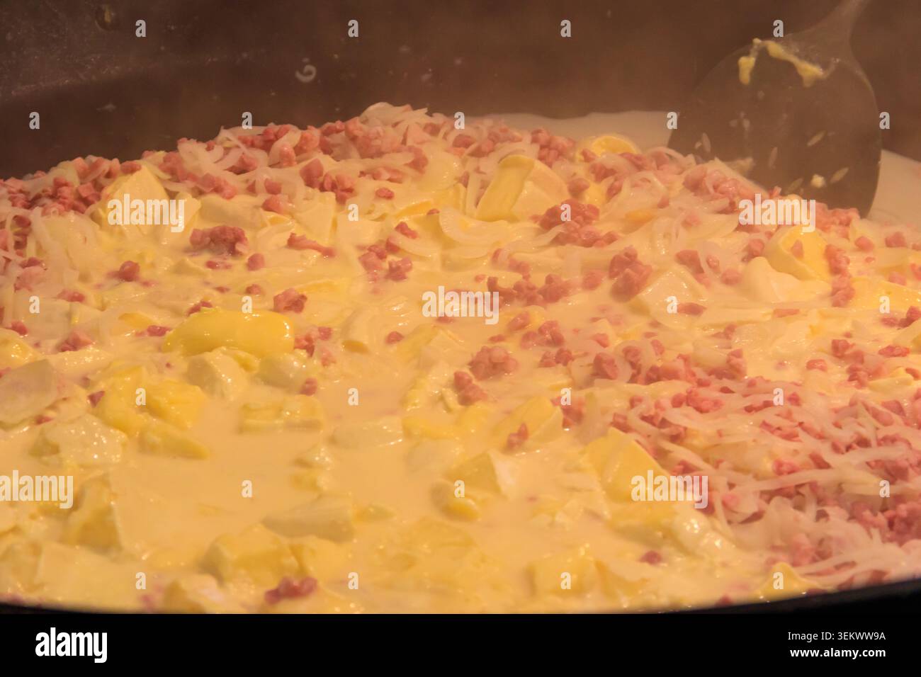 Zubereitung von Tartiflette, ein traditionelles französisches Gericht mit Jakobskartoffeln, Speck und Käse, in großem Kessel Stockfoto