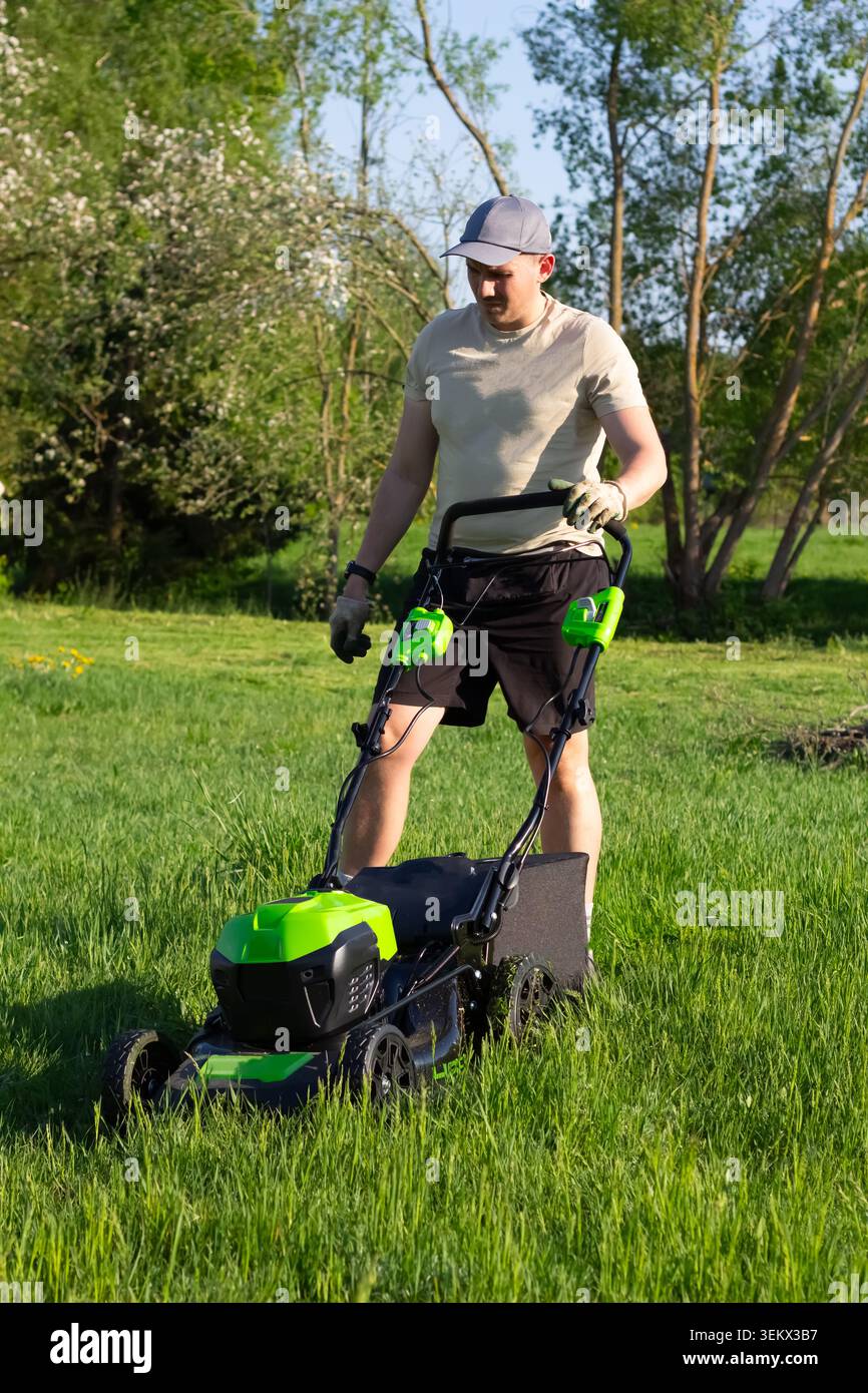 Ein Mann mäht das Gras mit einem kabellosen Rasenmäher Stockfoto