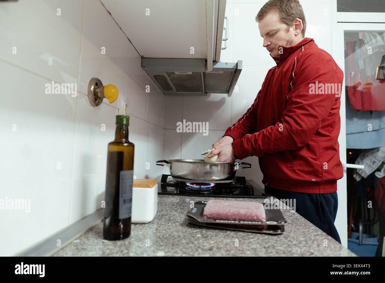 Mann, der in einer Küche Essen zubereitete, Zutaten für eine Mahlzeit hackte Stockfoto