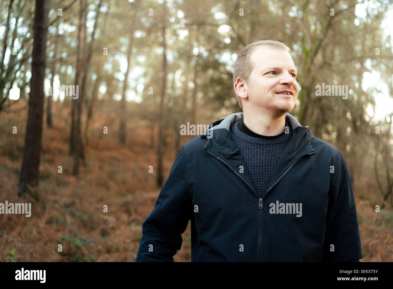 Ein Mann fühlt sich friedlich, blickt weg in einer ruhigen Waldumgebung Stockfoto