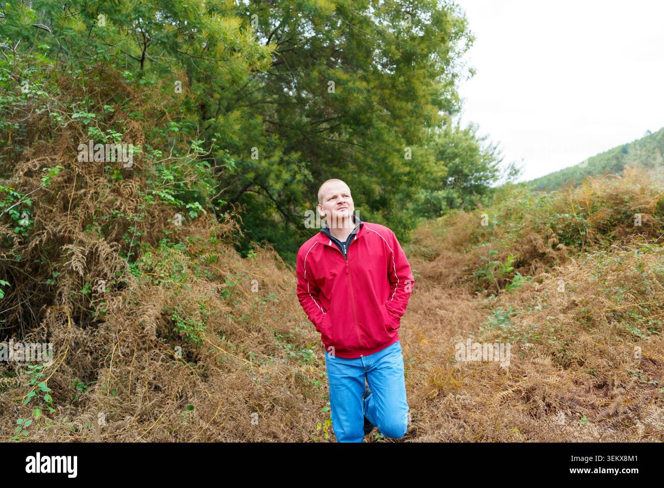Mann in roter Jacke, der einen besinnlichen Spaziergang in der Natur genießt Stockfoto
