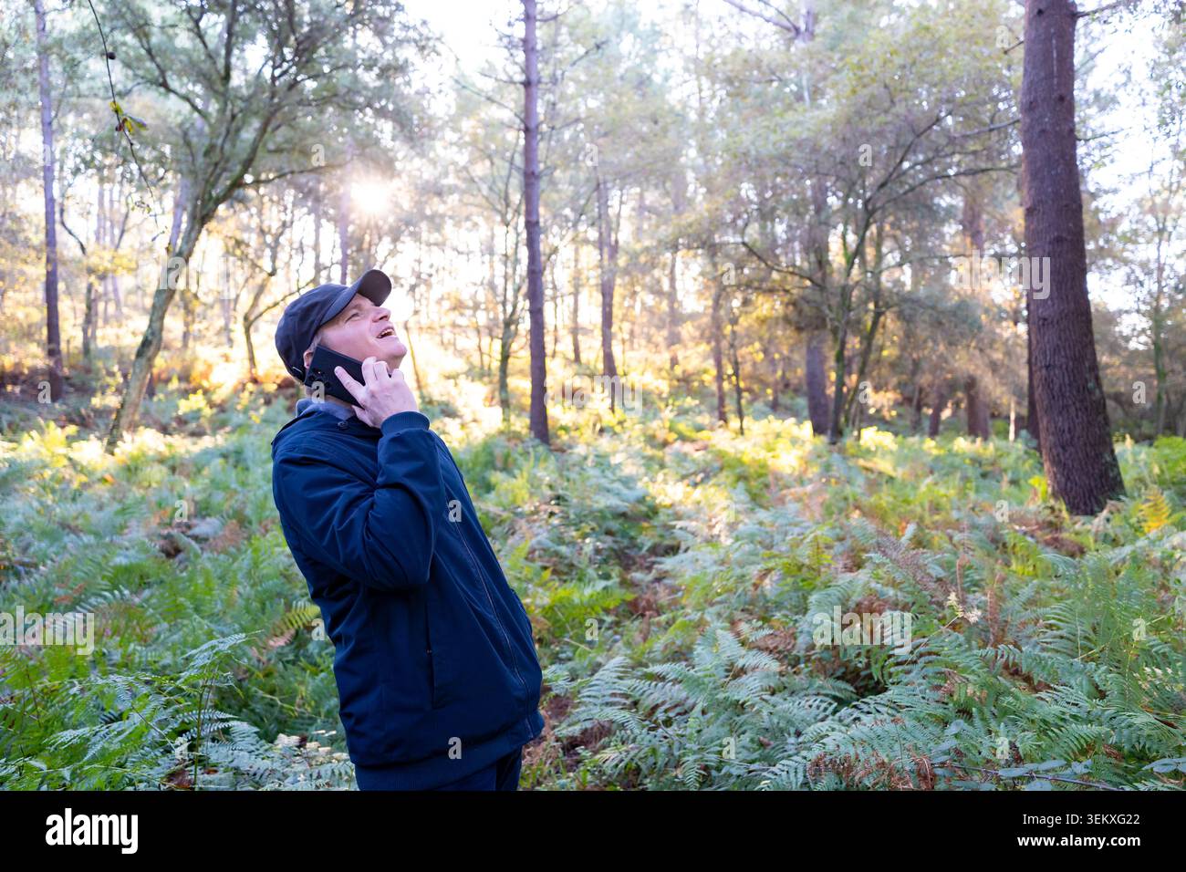 Mann, der draußen im Wald mit einem Handy kommuniziert Stockfoto
